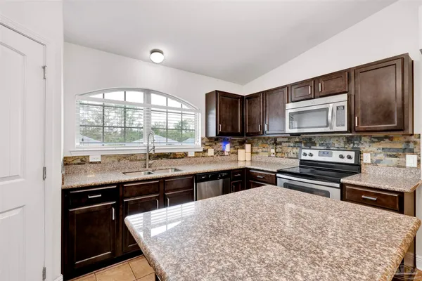 a kitchen with stainless steel appliances kitchen island granite countertop a stove top oven a sink dishwasher a dining table and chairs with wooden floor