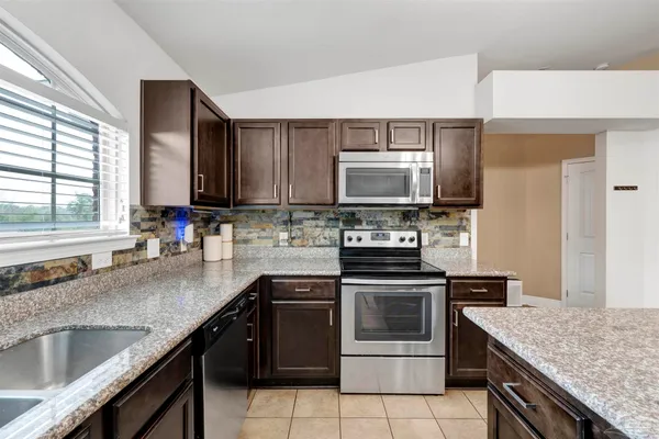 a kitchen with stainless steel appliances granite countertop a sink stove microwave and refrigerator
