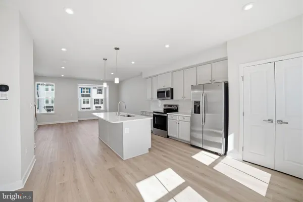 a kitchen with stainless steel appliances kitchen island wooden floors and white cabinets