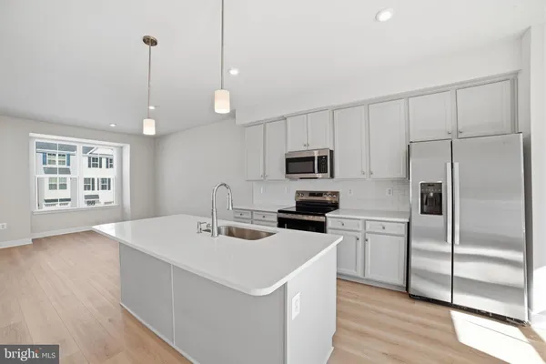 a kitchen with stainless steel appliances a stove a sink a refrigerator a center island with wooden floor