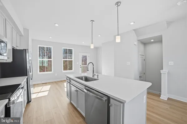 a kitchen with stainless steel appliances granite countertop a sink a microwave a center island and wooden floor