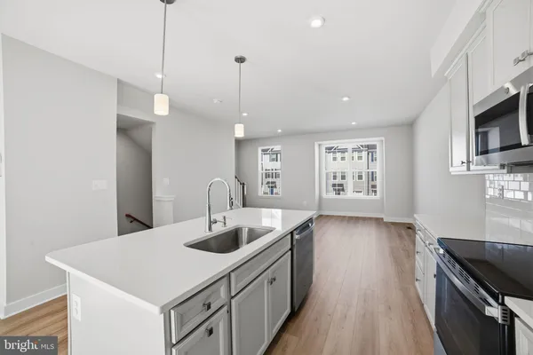 a kitchen with stainless steel appliances granite countertop a sink a stove and a wooden floors