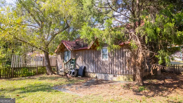 a backyard of a house with large trees and wooden fence