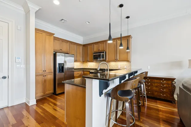 a kitchen with stainless steel appliances granite countertop a stove refrigerator and wooden floor