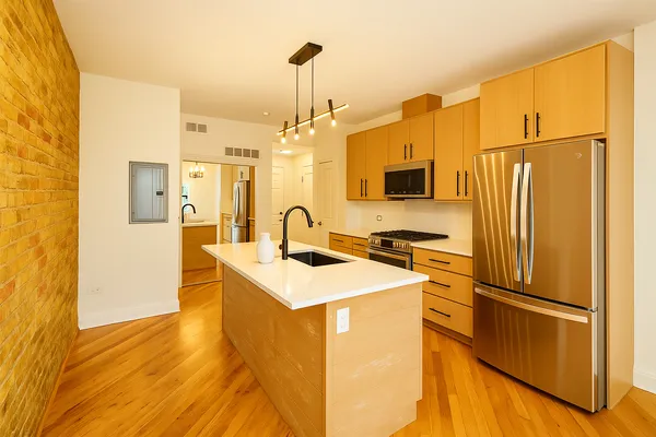 a kitchen with stainless steel appliances a refrigerator sink and wooden floor