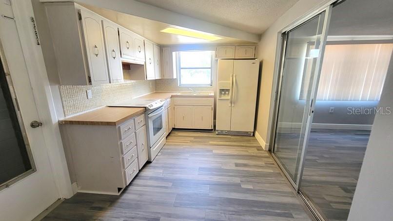 9202 Suffolk Lane Port Richey, FL 34668 - Photo 7 of 20 a kitchen with a sink a refrigerator a window and cabinets