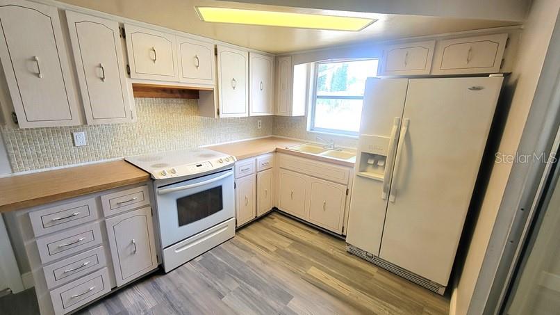 9202 Suffolk Lane Port Richey, FL 34668 - Photo 8 of 20 a kitchen with stainless steel appliances a stove a refrigerator a sink a cabinets and wooden floor