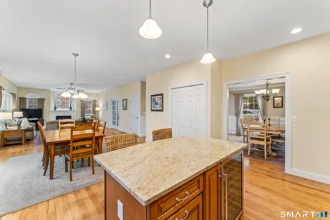 a view of a dining room and livingroom with furniture wooden floor a rug a flat screen tv a rug a fireplace and a chandelier