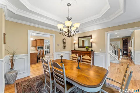 a dining room with wooden floor a chandelier a wooden table and chairs