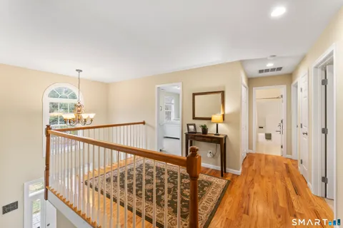 a view of a hallway to a livingroom with wooden floor and furniture