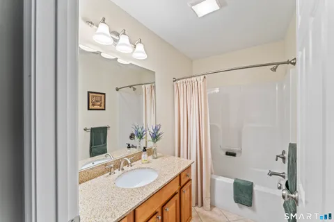a bathroom with a granite countertop sink a mirror and shower