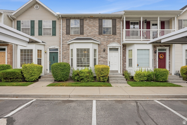 793 North 150 E Street Springville, UT 84663 - Photo 1 of 26 Townhome exterior featuring a mix of brick and siding, bay windows, a covered balcony with white railings, and manicured shrubbery