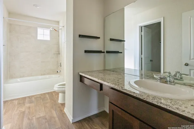 a bathroom with a granite countertop sink a toilet and bathtub