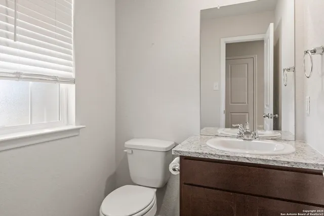 a bathroom with a granite countertop toilet sink and mirror