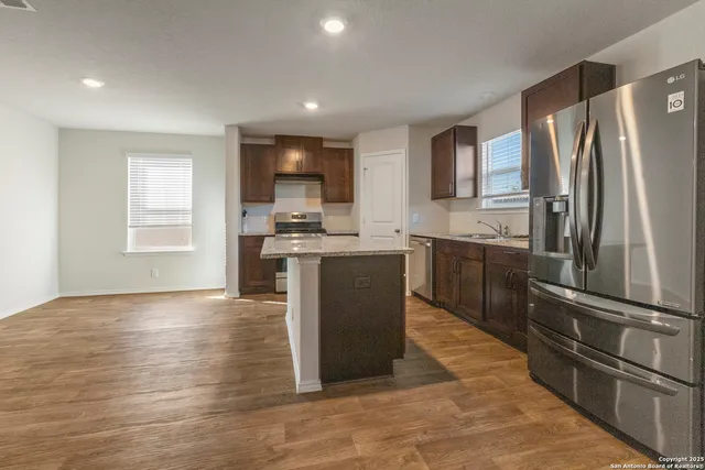 a kitchen with stainless steel appliances granite countertop a refrigerator a sink and a stove