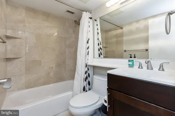 a bathroom with a bathtub shower sink vanity mirror and toilet