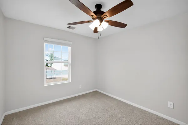 an empty room with a window and a fan