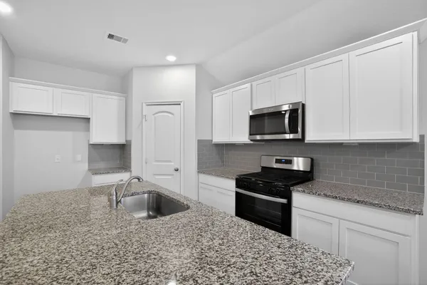 a kitchen with granite countertop a sink a stove a microwave and refrigerator