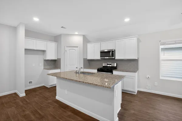 a kitchen with stainless steel appliances granite countertop a sink stove microwave and refrigerator