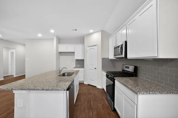 a kitchen with granite countertop kitchen island a sink stainless steel appliances and white cabinets