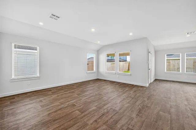 a view of an empty room with window and wooden floor