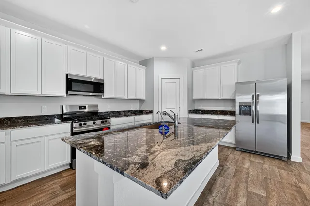 a kitchen with stainless steel appliances granite countertop a sink a stove and a refrigerator
