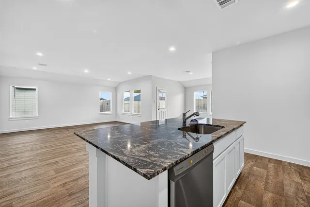 a kitchen with granite countertop kitchen island a sink and a refrigerator