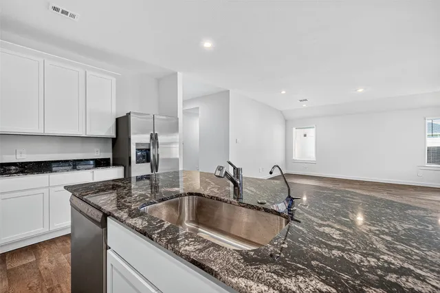 a kitchen with granite countertop a sink a stove and refrigerator