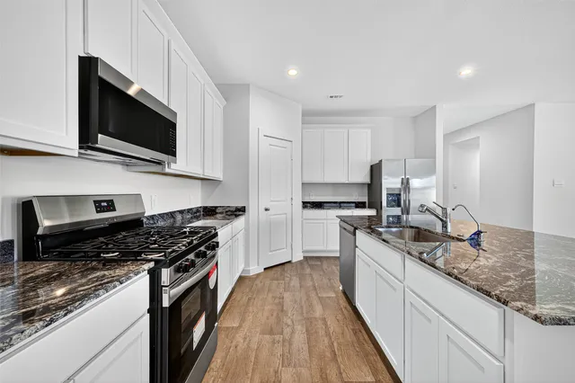 a kitchen with stainless steel appliances granite countertop a stove a sink and a microwave