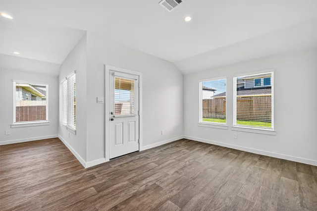 an empty room with wooden floor and windows
