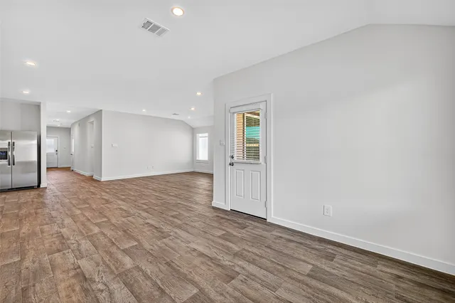 a view of empty room with wooden floor
