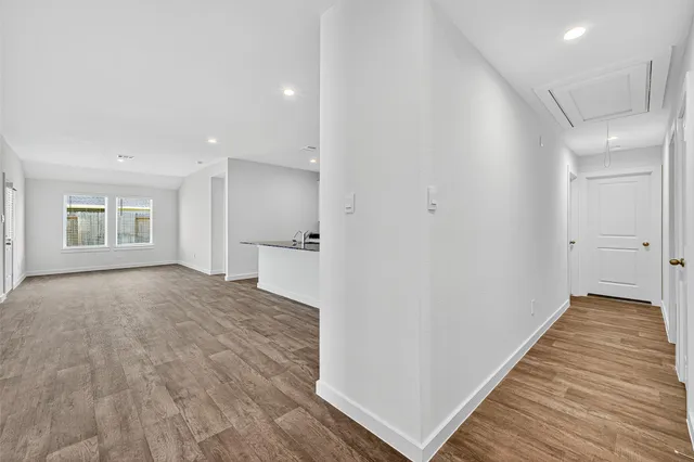 a view of a hallway with wooden floor and a bathroom