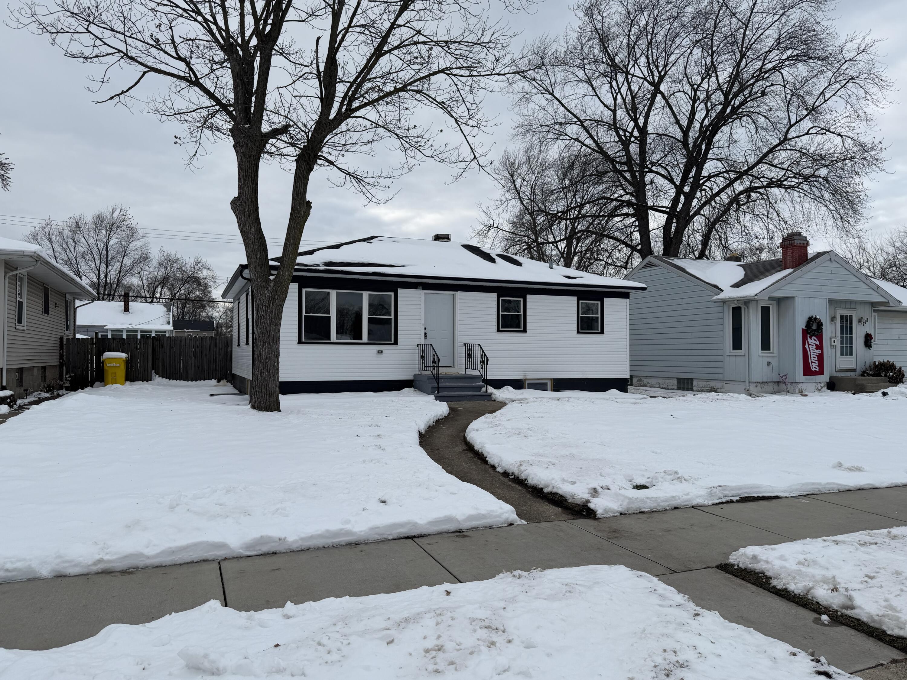 a front view of a house with trees and covered with snow