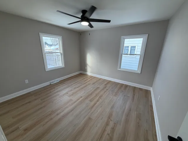 a view of an empty room with a window and wooden floor
