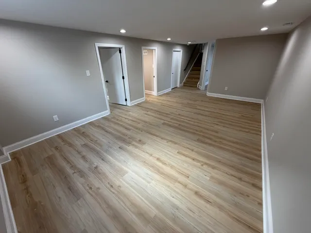 an empty room with wooden floor and natural light