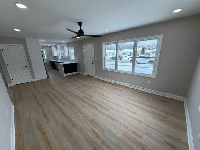 a view of an empty room with wooden floor and a window