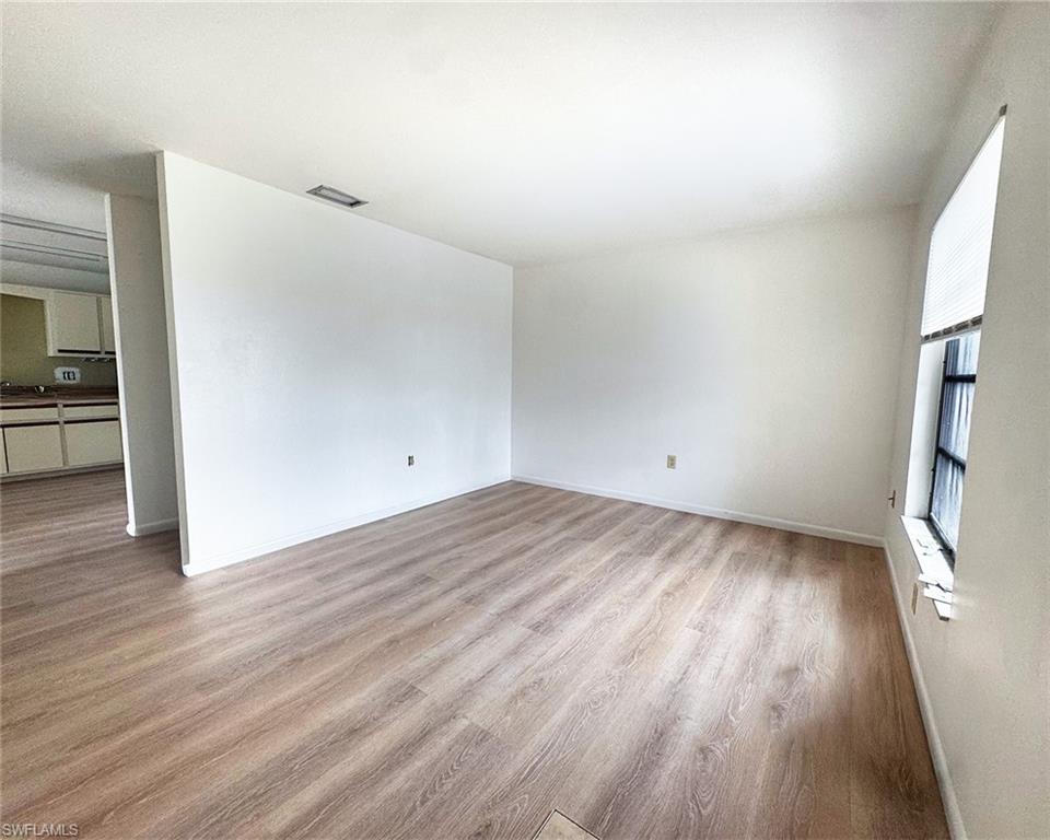 699 110th Avenue North, Unit A Naples, FL 34108 - Photo 3 of 15 wooden floor in an empty room with a window