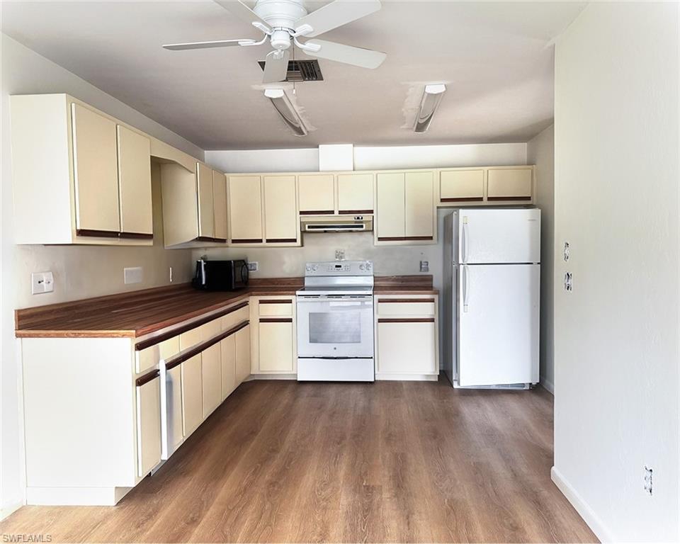 699 110th Avenue North, Unit A Naples, FL 34108 - Photo 4 of 15 a kitchen with a refrigerator a stove top oven a counter space and wooden floor