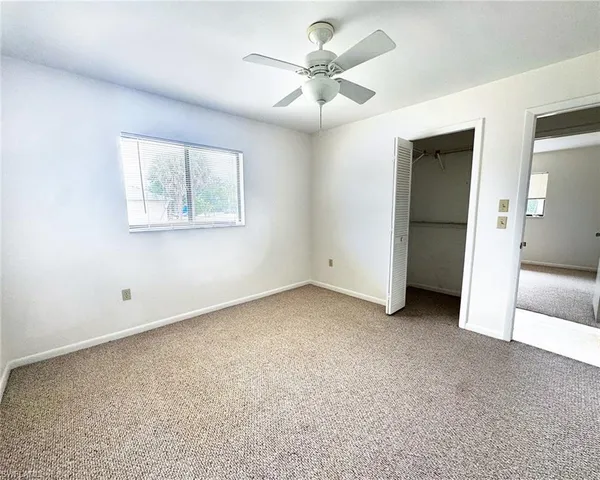 an empty room with a ceiling fan and a window
