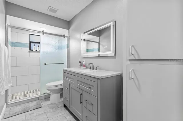 a bathroom with a granite countertop sink toilet and shower