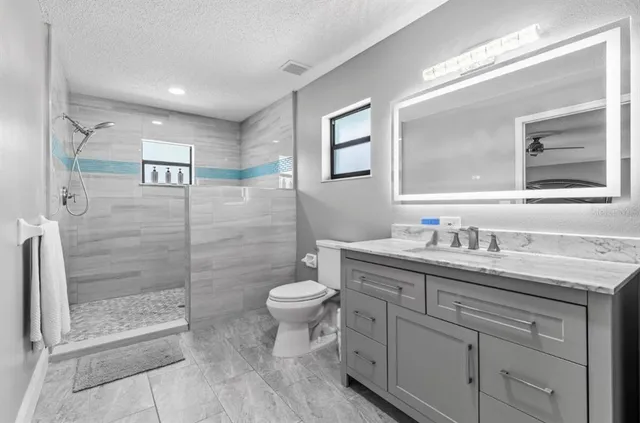 a bathroom with a granite countertop sink toilet and shower