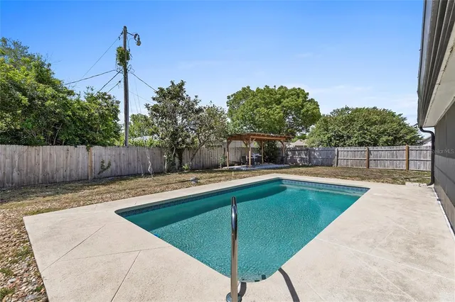 a view of a backyard with swimming pool in the backyard