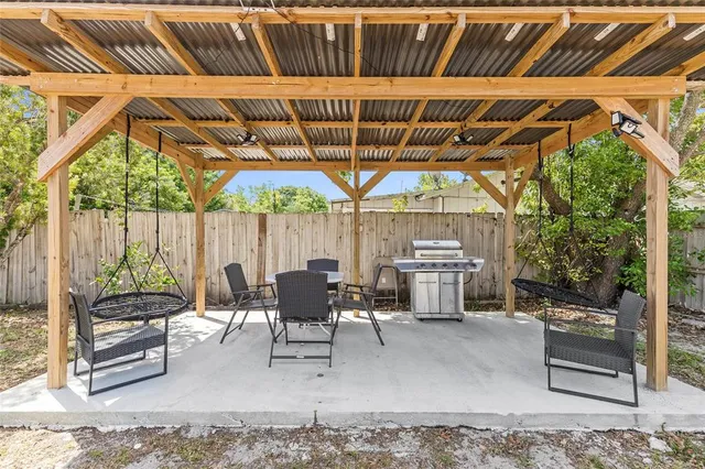 a view of a patio with table and chairs under an umbrella with a barbeque grill and couches
