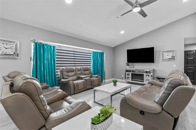 a living room with furniture a flat screen tv and a large window