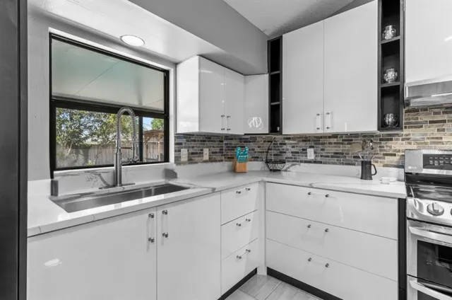a kitchen with white cabinets and sink