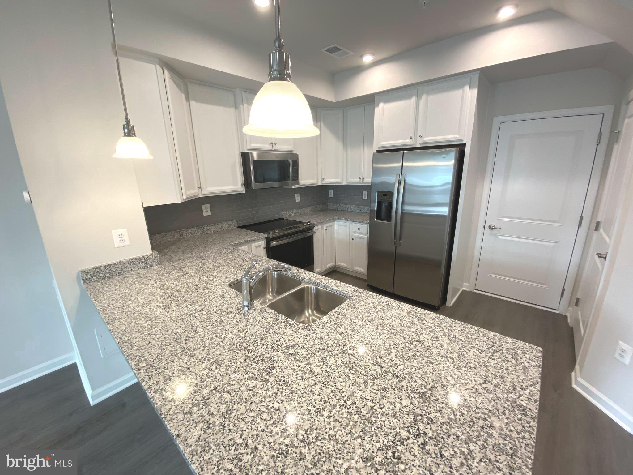 7911 Independence Drive, Unit 1C Spotsylvania, VA 22553 - Photo 11 of 35 a kitchen with stainless steel appliances granite countertop a refrigerator a sink a stove and a counter top space