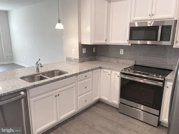 a kitchen with granite countertop white cabinets and a stove top oven