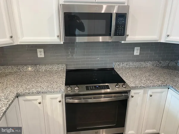 a kitchen with granite countertop white cabinets and stainless steel appliances