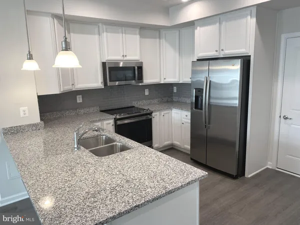 a kitchen with stainless steel appliances granite countertop a sink a stove and a refrigerator