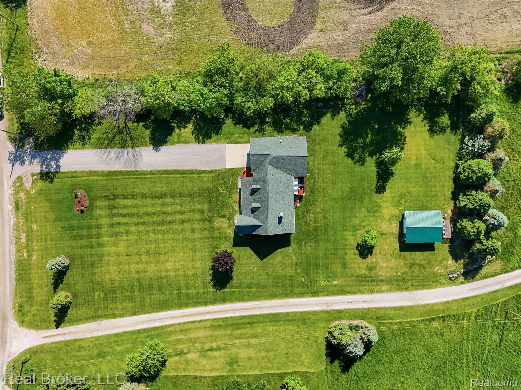 7271 West Ray Road Gaines, MI 48436 - Photo 6 of 48 Expansive verdant grounds featuring a main residence with a green roof, a detached shed, a paved driveway, and mature perimeter trees